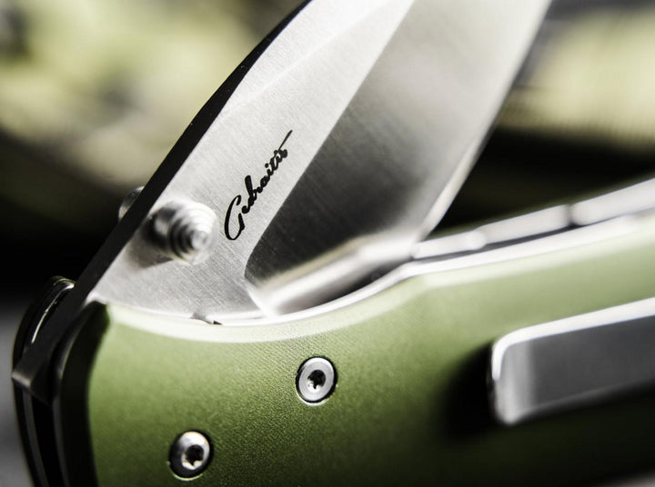 Close-up of the Böker Plus Lefti blade with signature etching and olive green handle with pocket clip