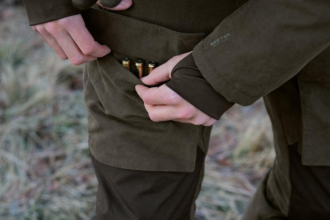 Close-up of a hand loading cartridges into the belt loop holder on the Seeland Helt II trousers