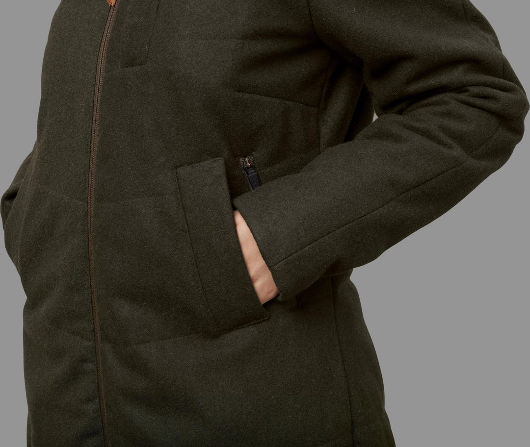 Side detail of the Härkila Metso Winter jacket showing the front zip line and a hand entering the zipped hand pocket.