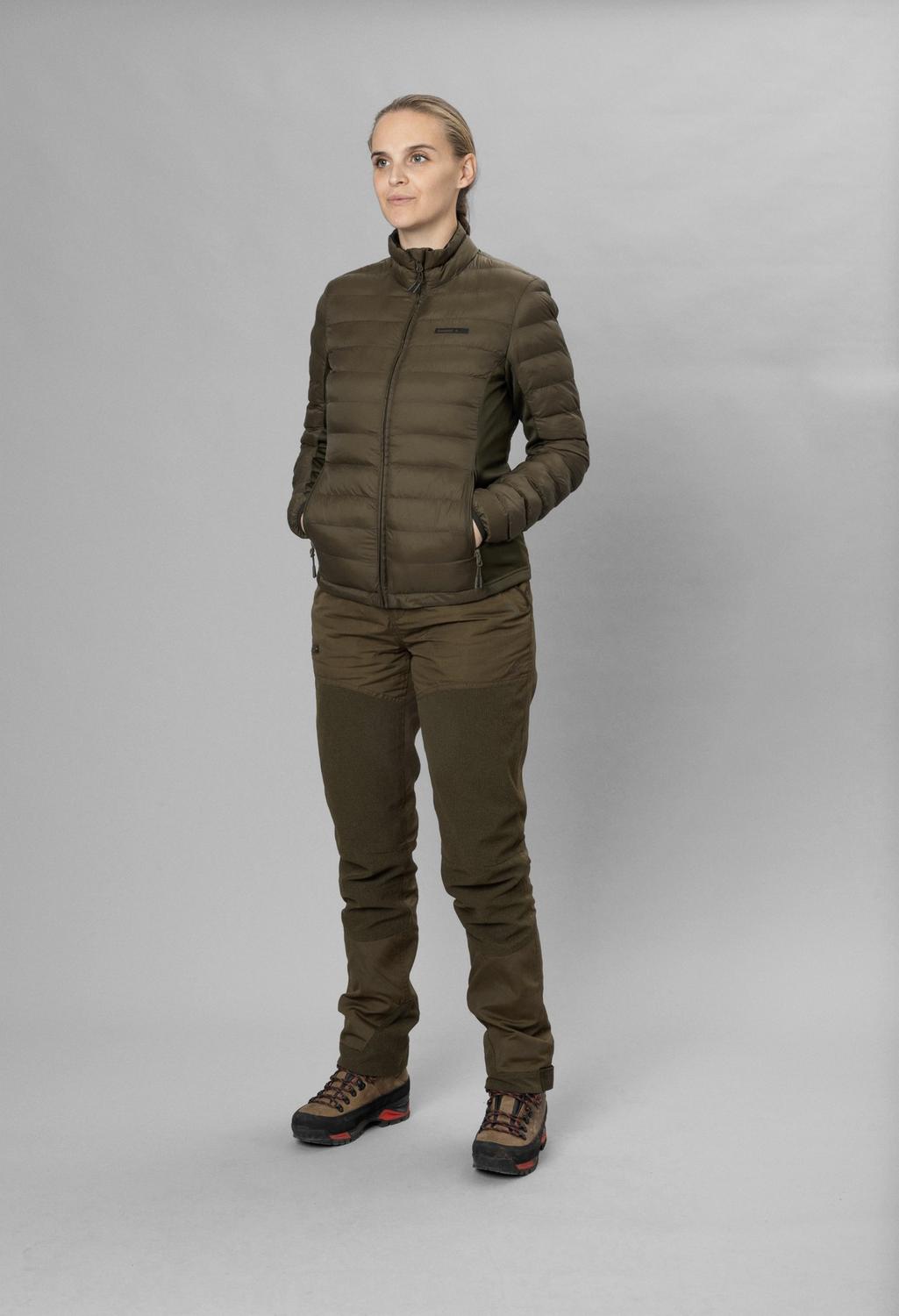 Full-length front view of a model wearing the olive Seeland Therma Puffer Jacket over matching trousers and brown walking boots, grey studio backdrop.