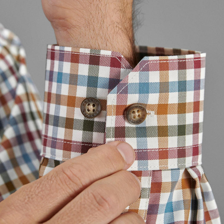 Close-up of a hand fastening the buttoned cuff of the multi-check Härkila Milford shirt