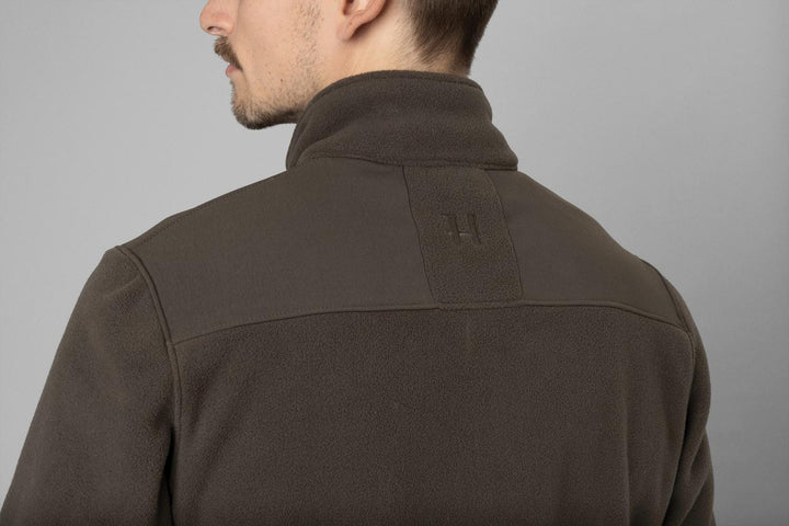 Close-up on a model: rear shoulder and collar of the olive fleece with the embossed Harkila logo on the yoke