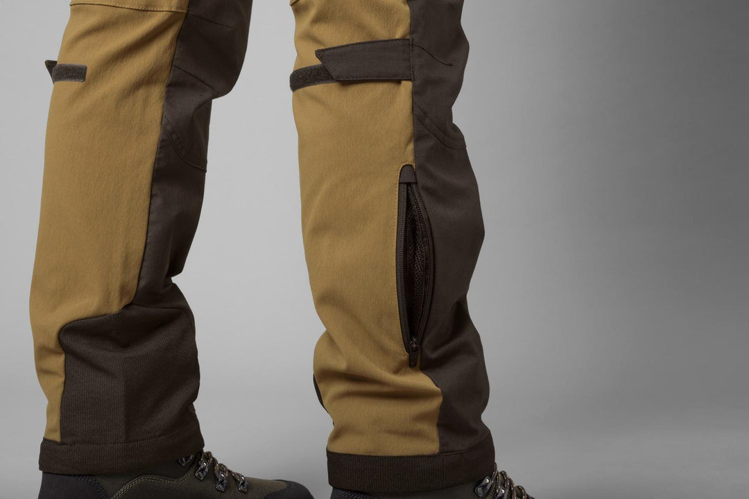 Close-up of the Härkila Ragnar trouser lower legs with the side leg zip open over brown leather boots
