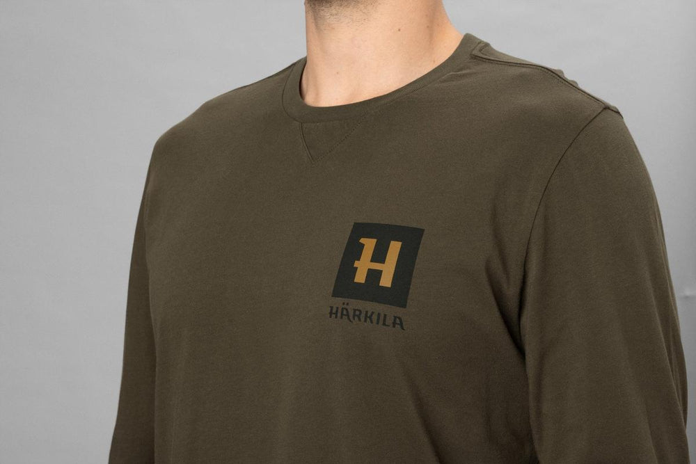 Close-up of the Harkila logo patch on the chest of the Gorm L/S t-shirt in Willow olive